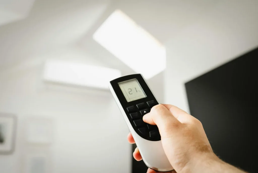 A hand holding an air conditioning remote control.
