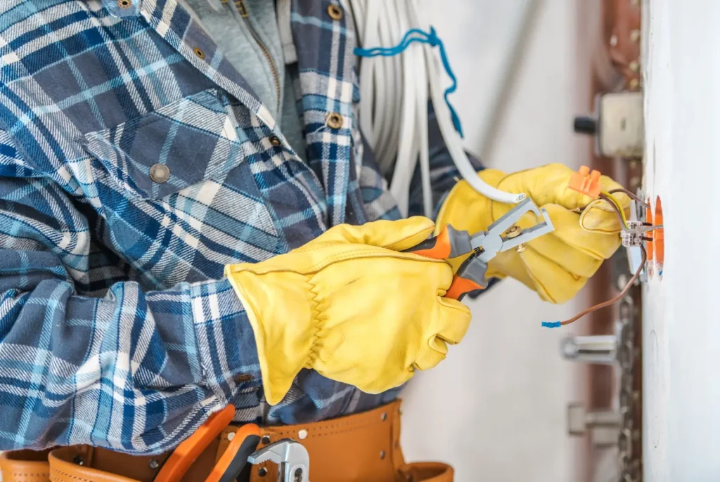 an electrician wearing safety gloves works on wiring