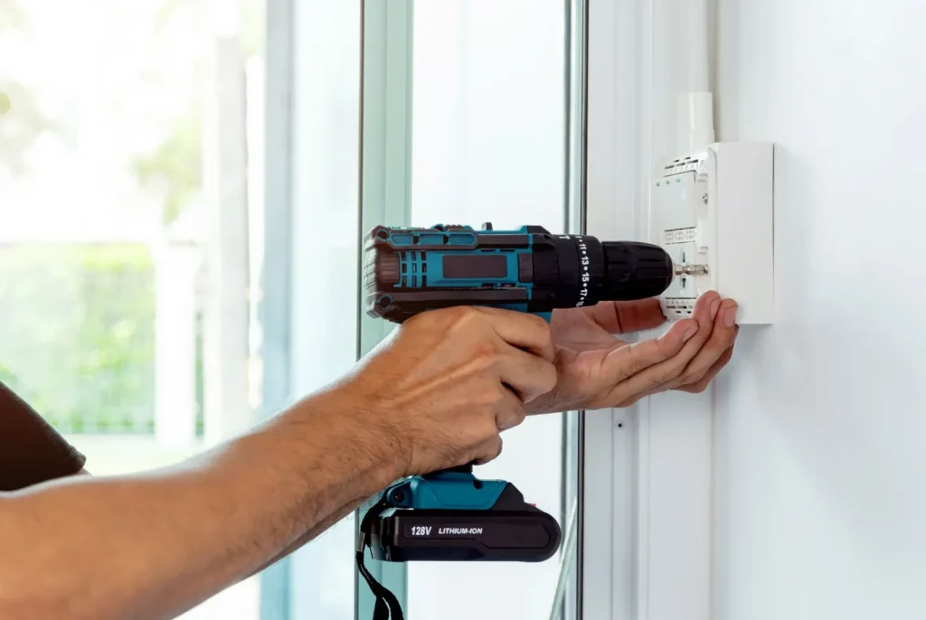 A technician installs a dimmer switch with a drill.