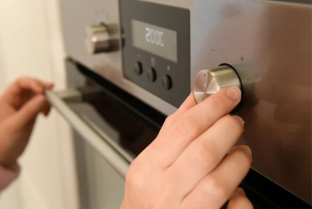 A hand adjusting the temperature on an electric oven.